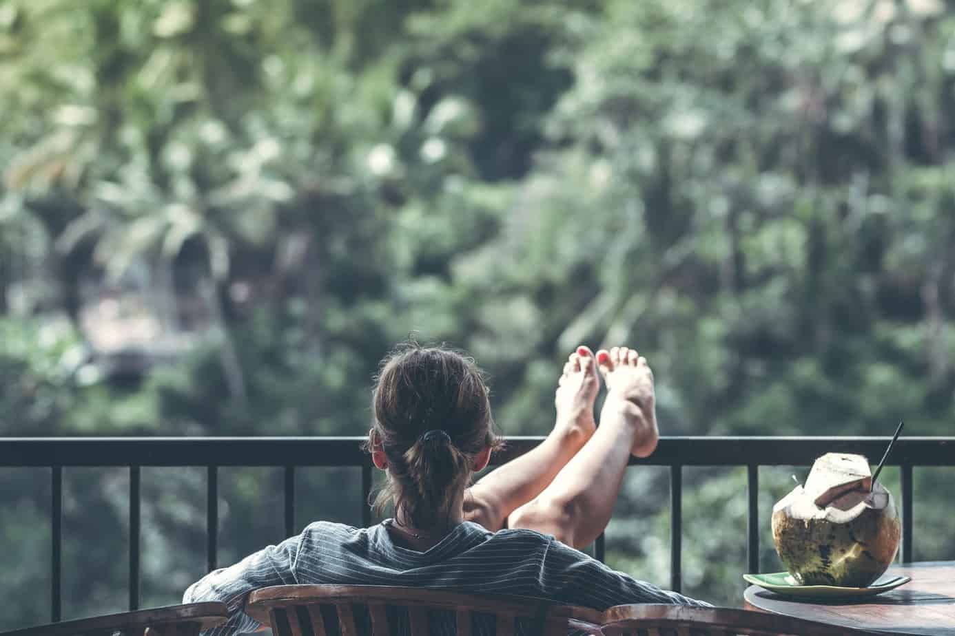 woman sitting on brown wooden chair beside coconut