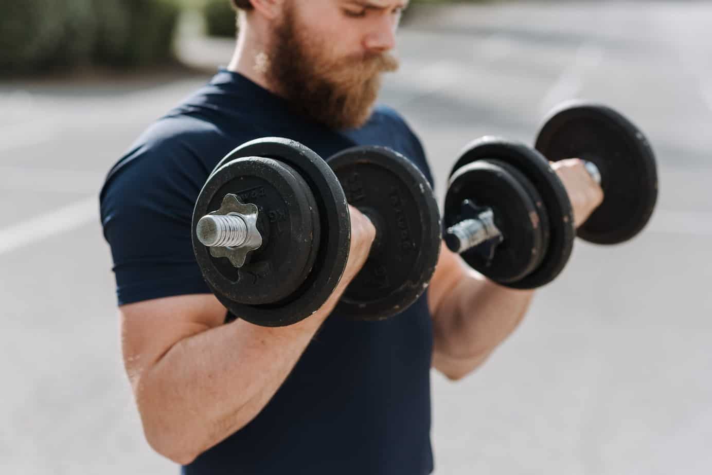 strong man training biceps with dumbbells